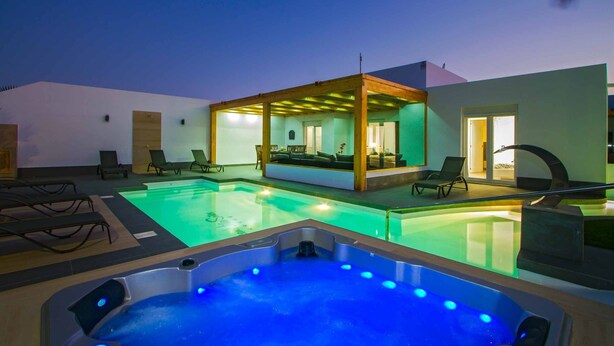 Zona de piscina amb gandules, banyera d'hidromassatge i zona d'estar coberta.