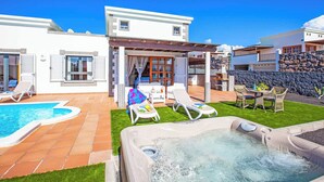 Une villa moderne dotée d’une piscine, d’un jacuzzi et d’un patio aménagé avec du mobilier d’extérieur.
