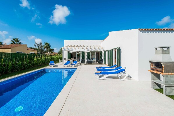 A swimming pool with lounge chairs, a barbecue area, and a covered patio.