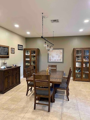 A dining room with a wooden table and chairs, a chandelier, and built-in cabinets.