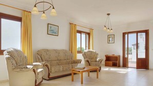 A spacious living room with a sofa, armchairs, a coffee table, and a wooden side table. - Villa La Pinta - Five Bedroom Villa, Sleeps 10 (Cala d'Or)