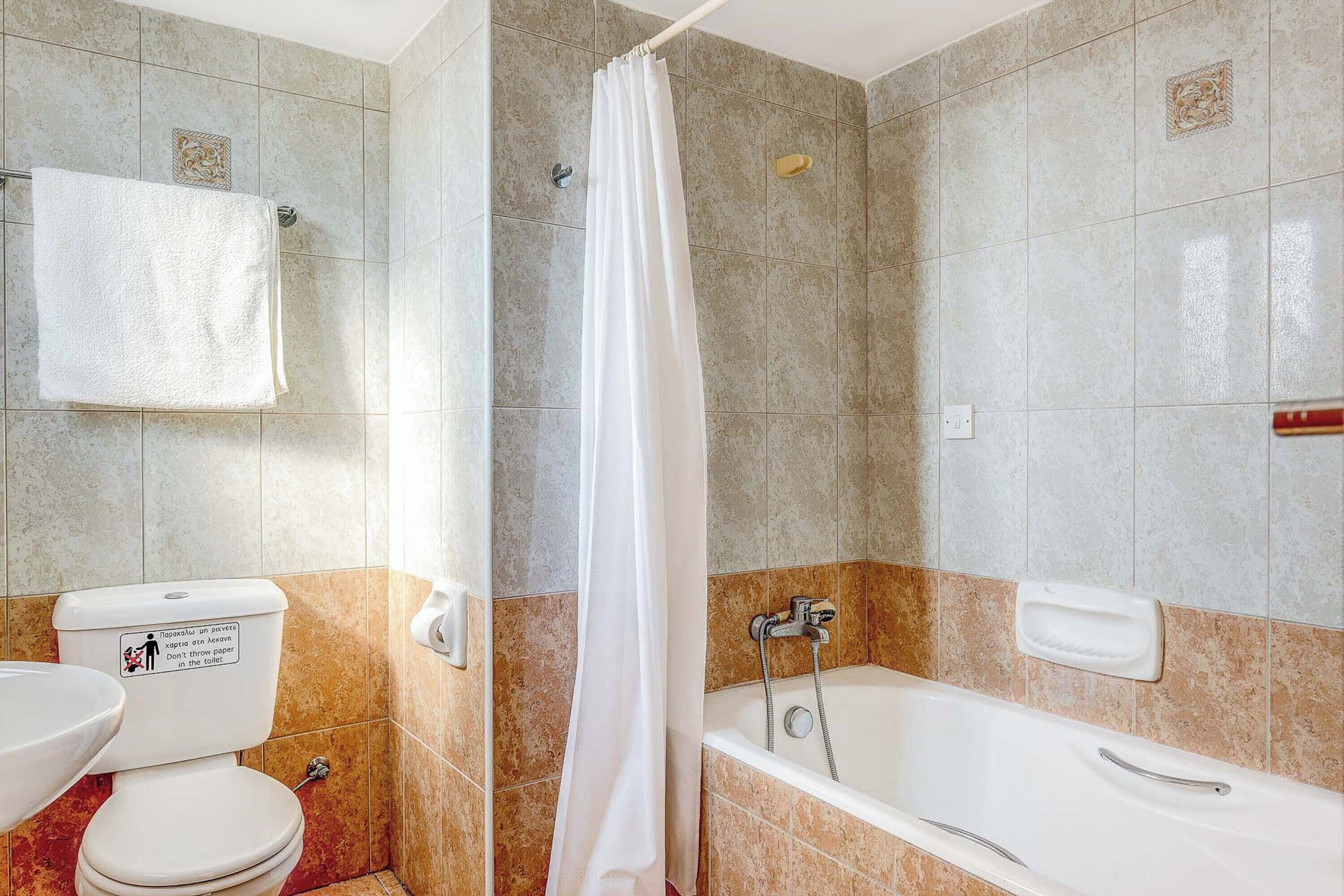A bathroom with a toilet, sink, bathtub, and shower curtain.