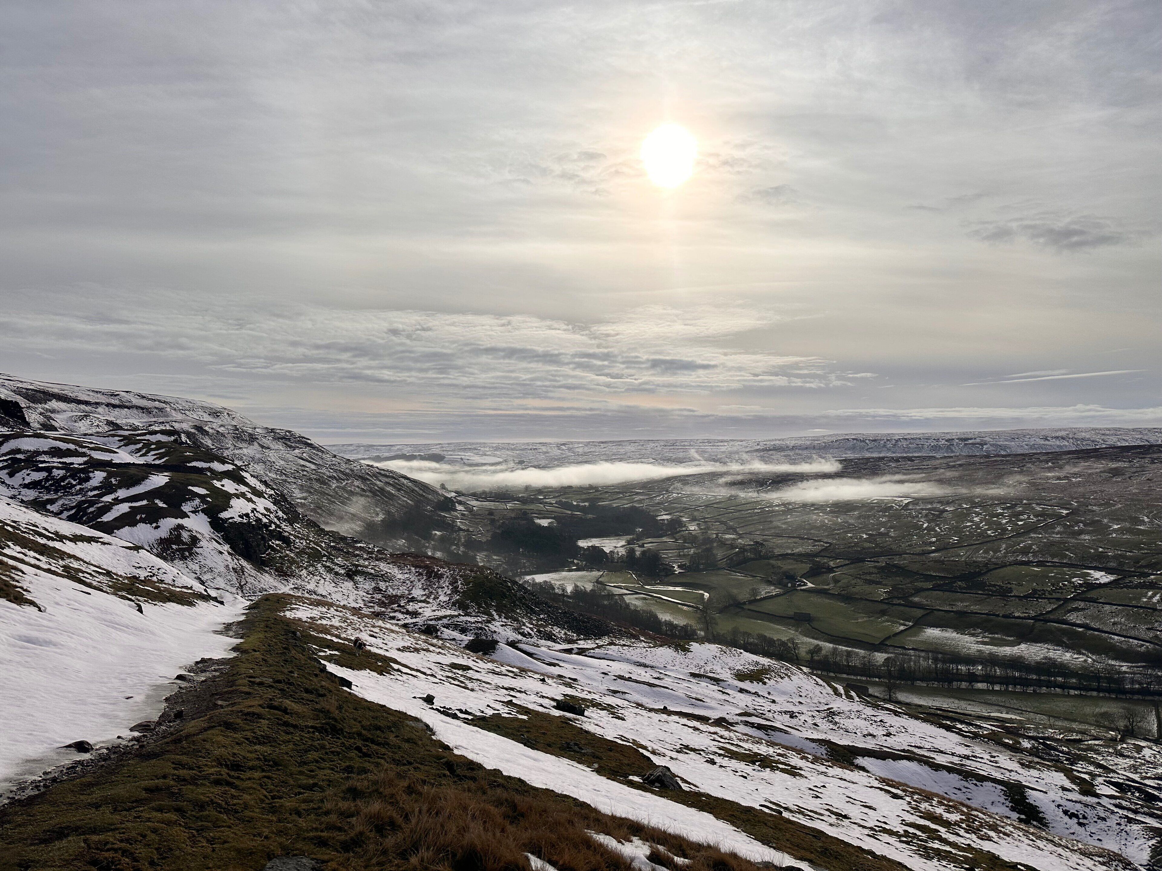 Une vue panoramique d’un paysage montagneux, avec des pentes enneigées et une vallée en contrebas.