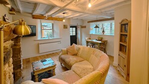 Een gezellige woonkamer met een bank, een salontafel, een open haard, een boekenkast en een raam.