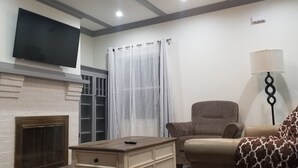 A living room with a fireplace, a television mounted on the wall, a sofa, and a lamp. - Newly Renovated Open-Concept living space, close to Boston, plenty of parking (Milton)