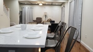 A dining area with a white marble table set for four, surrounded by chairs. - Newly Renovated Open-Concept living space, close to Boston, plenty of parking (Milton)