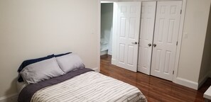 A bedroom with a bed, a wardrobe, and a door leading to another room.