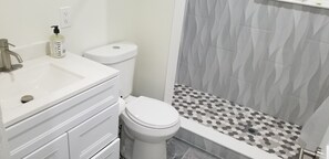 A bathroom with a white sink, a toilet, and a shower with patterned tiles.