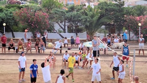 Un terrain de beach-volley sablonneux, avec des joueurs et des spectateurs.
