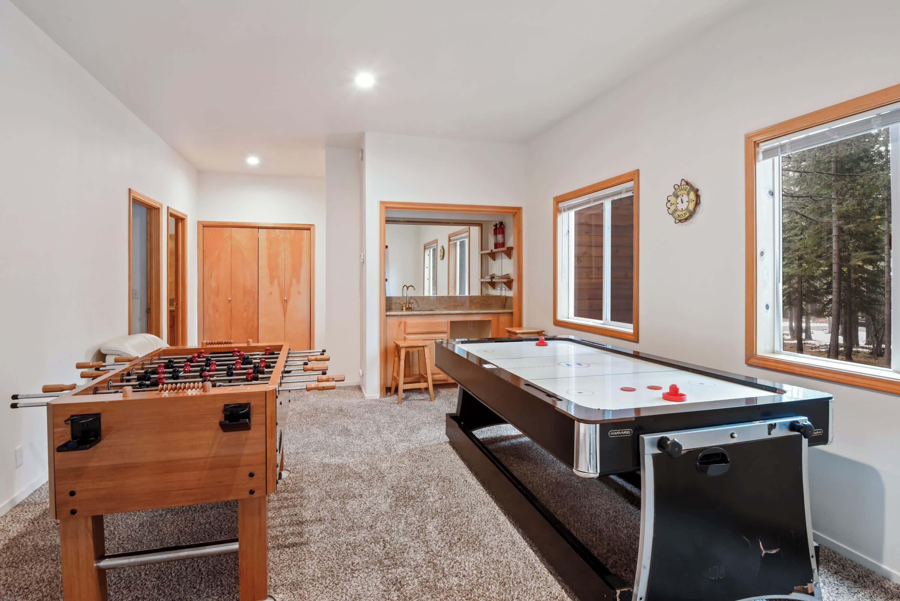 A room with a foosball table, a pool table, and a wooden wardrobe.