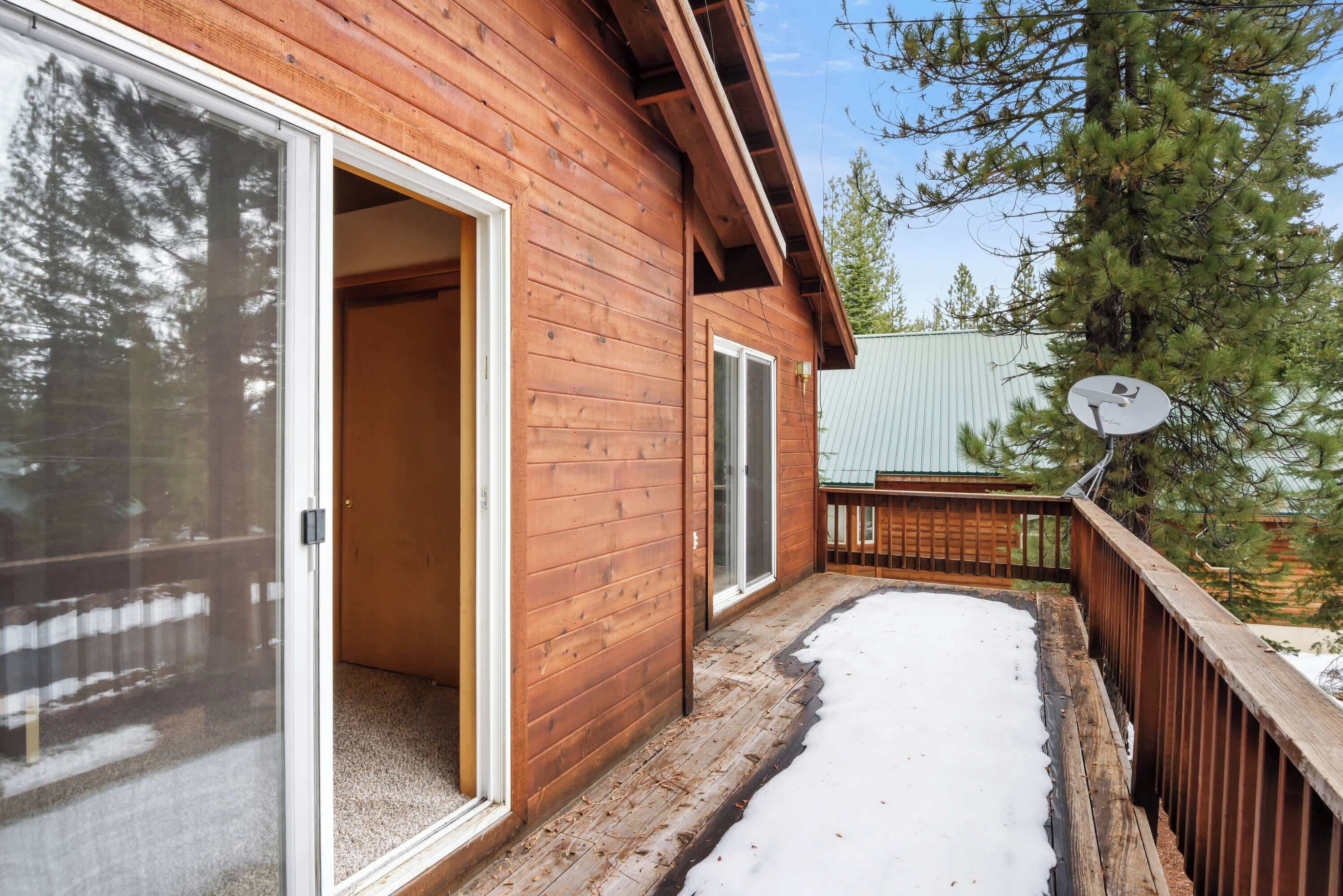 Una cabaña de madera con un porche cubierto y un sendero cubierto de nieve.