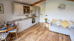 A spacious kitchen with wooden cabinets and a dining area with a table set for four. - Celyn (Ruthin)