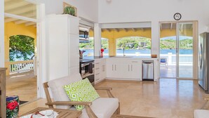A spacious living area with a view of the sea, a kitchen with white cabinets, and a dining area with wooden furniture. - Wake up in paradise at this amazing villa for couples and families (St.Paul)