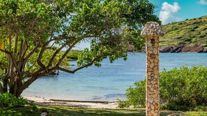 A stone pillar with a decorative top, surrounded by lush greenery and a clear view of a calm body of water. - Wake up in paradise at this amazing villa for couples and families (St.Paul)