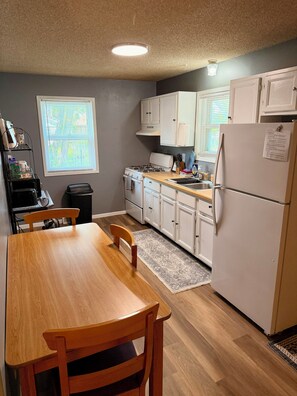 A kitchen with a dining table, chairs, a stove, cabinets, and a refrigerator. - Great location duplex (Stevens Point)