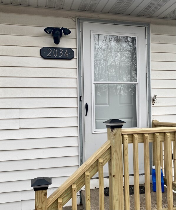 A house with a white exterior, a front door with a glass panel, and a wooden staircase leading up to the door. - Great location duplex (Stevens Point)