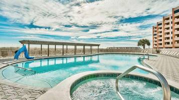 Relax by the oval-shaped pool surrounded by a tiled deck and a hot tub with water jets.