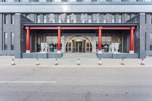 Un edificio con una entrada amplia, pilares rojos y estatuas.