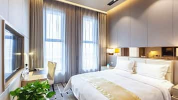 A modern hotel room with a large bed, a bedside table, a lamp, and a TV.