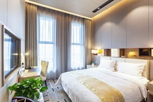 Una habitación de hotel moderna con una cama grande, una mesita de noche, una lámpara y un televisor.