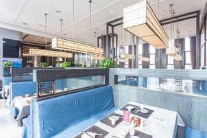 Un restaurante moderno con techos altos, iluminación colgante y una zona de estar azul.