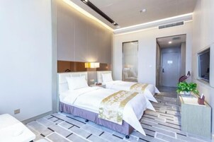 Habitación de hotel moderna con una cama grande, mesitas de noche, un televisor y un baño.