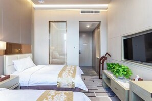 A hotel room with two beds, a TV, a plant, and a desk. - Fengze Business Hotel (Fanshi)