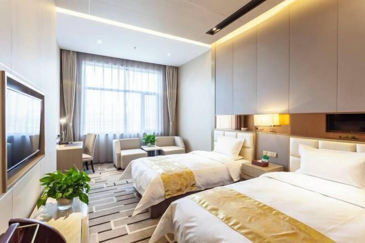 A hotel room with two beds, a TV, a desk, and a chair.