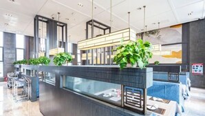 Una zona de recepción moderna con mostrador oscuro, divisiones de vidrio y plantas colgantes.