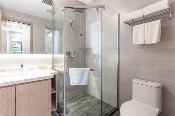 A modern bathroom with a glass shower enclosure, a toilet, and a vanity with a mirror. - Fengze Business Hotel (Fanshi)