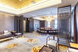 A spacious room with a round table, seating, and a chandelier. - Fengze Business Hotel (Fanshi)