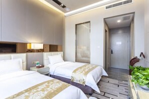 A hotel room with two beds, a bedside table with a lamp, a mirror, and a door leading to another room. - Fengze Business Hotel (Fanshi)