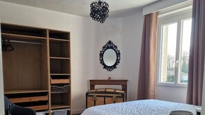 Un dormitorio con una cama grande, un armario, una cómoda, un espejo y una ventana con cortinas.