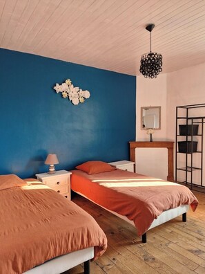 Ein Schlafzimmer mit zwei Betten, einem Nachttisch, einer Kommode, einem Spiegel und einer Deckenleuchte.