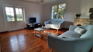 Una sala de estar con piso de madera, un sofá, un televisor y una chimenea.