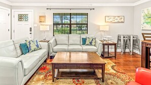 A living room with a sofa set, a coffee table, a window with blinds, a lamp, and a painting on the wall.