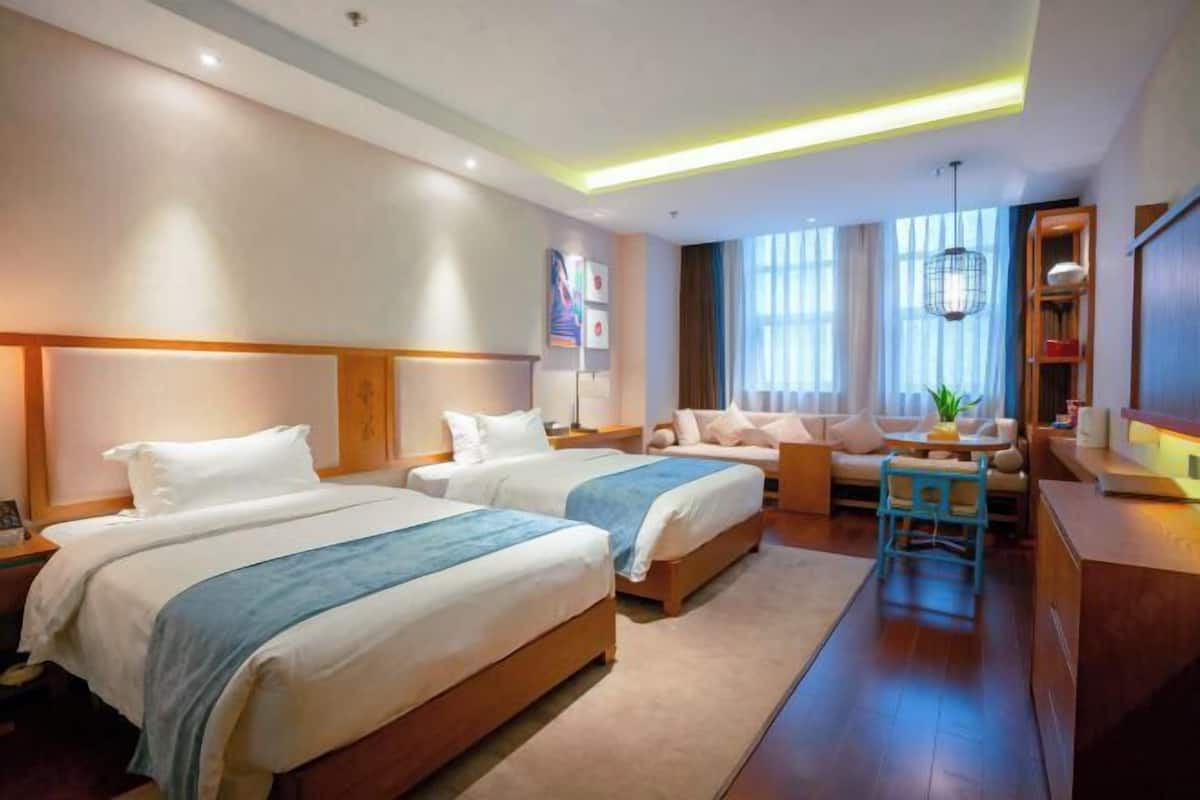Habitación de hotel con dos camas, un sofá, un escritorio y una silla.