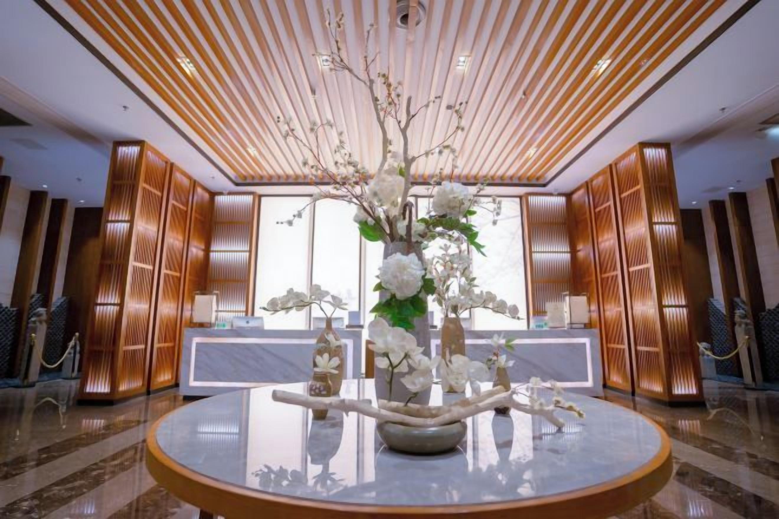 A lobby with a round marble table, a decorative centerpiece, and a modern ceiling design.