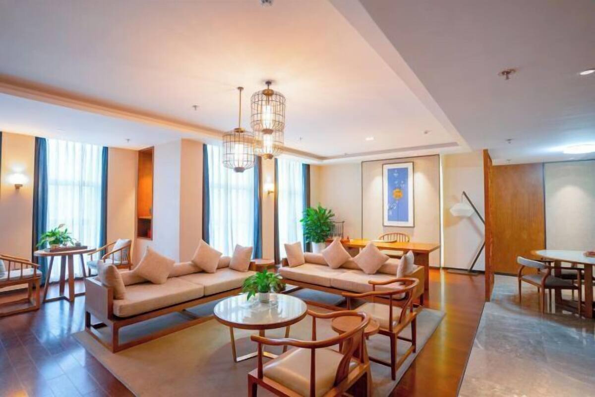 Un moderno vestíbulo de hotel con un conjunto de sofás, mesas redondas y una planta grande.