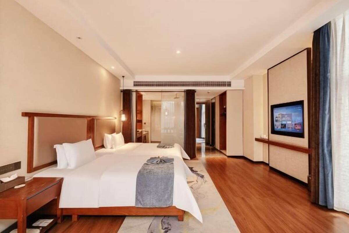 Habitación de hotel con una cama grande, un escritorio, un televisor y vista al pasillo.