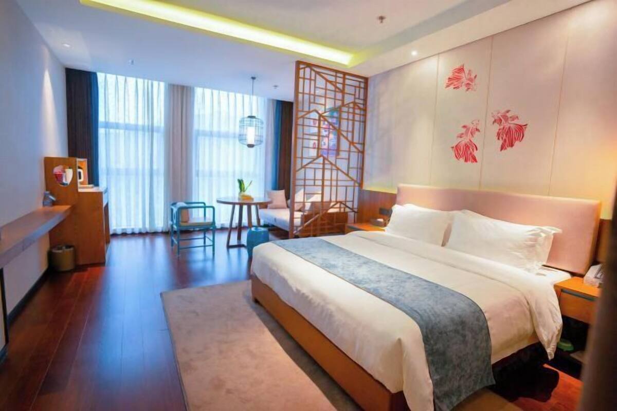 Una habitación de hotel moderna con una cama grande, un escritorio, una silla y una mesita.