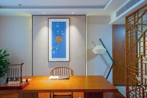 A modern dining area with a wooden table, a chair, a framed artwork on the wall, and a floor lamp. - Zhongyi Hotel (Zhong County)