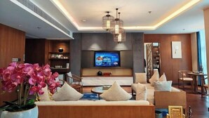 Uma sala de estar moderna com sofá, televisão e iluminação decorativa.
