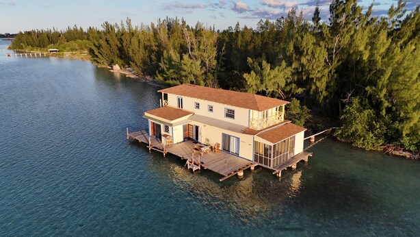 A waterfront house with a deck and multiple rooms, surrounded by trees and water. - Sunset Point Houseboat, a gem of a place (Fresh Creek)