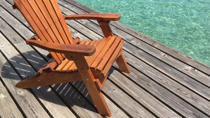 A wooden deck with a single wooden chair facing a clear turquoise sea. - Sunset Point Houseboat, a gem of a place (Fresh Creek)