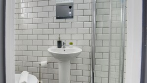 A bathroom with a white tiled wall, a pedestal sink, a toilet, and a glass shower enclosure. - 56HRC 5 BedRoom House| Garden| Parking PFP (Coventry)