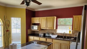 Une cuisine avec des meubles de rangement en bois, un four à micro-ondes, un grille-pain et une cuisinière.