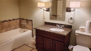 Une salle de bain équipée d’une baignoire, d’un lavabo, d’un meuble-lavabo, d’un miroir et de toilettes.
