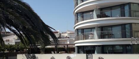 A modern multi-story building with a pool in front.