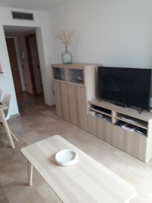 Un soggiorno moderno con una panca di legno, una televisione su un mobile e un armadio con ante in vetro.